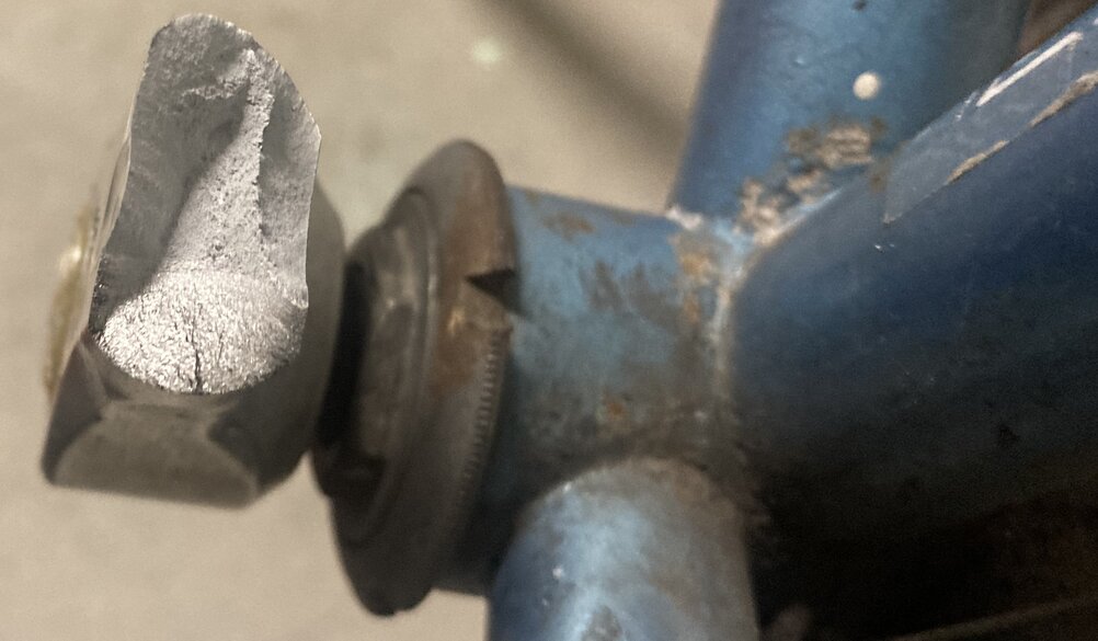 Broken bicycle pedal with Peugeot logo upside down. Bike frame in the background. Close up of crack