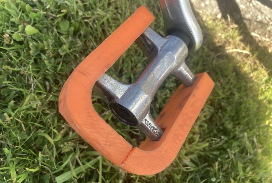 Bike pedal made of orange plastic, broken. Top view