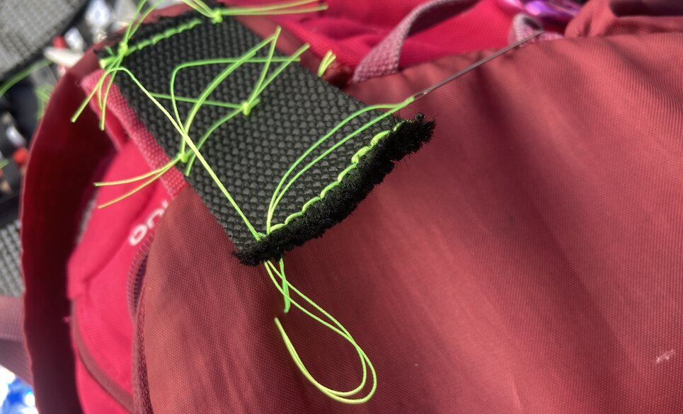 Initial stitches in yellow thread to align the webbing and backpack