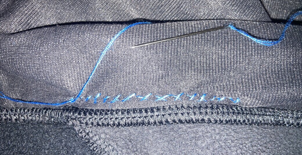 Black fabric with blue thread forming an X in a regular interval