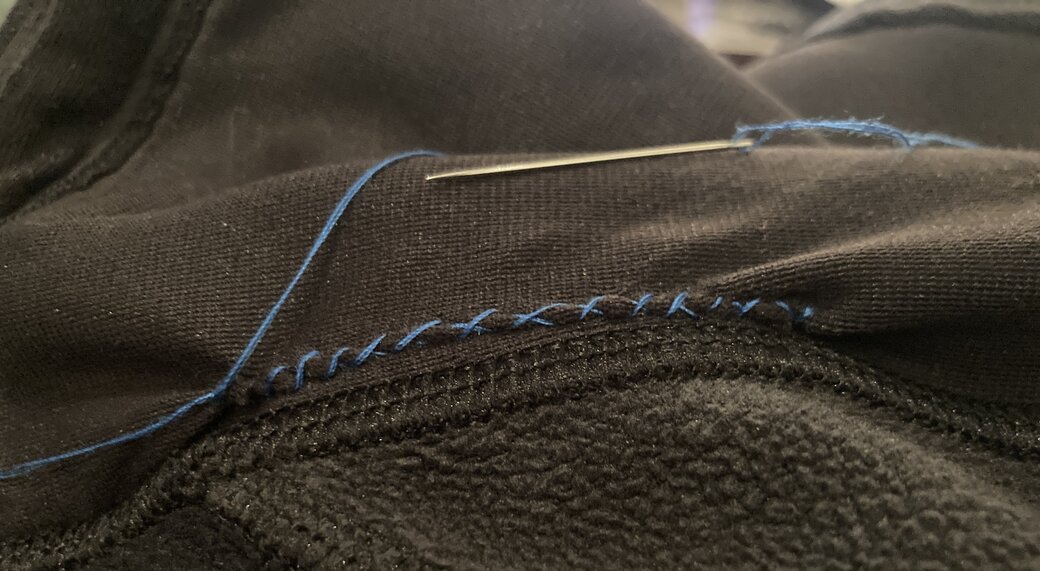 Black fabric with blue thread forming an X in a regular interval. Zoomed out view